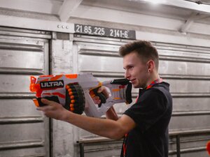 Young employee holding a Nerf gun and aiming at the cans.
