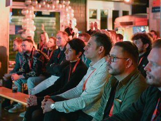Guests in the front rows sit and look to the front. They listen intently to the two speeches and continue to educate themselves. | © instride AG