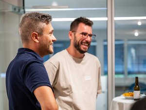 Zwei Männer lächeln und unterhalten sich beim BeerTalk.