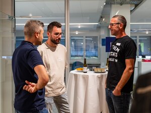 Drei Männer unterhalten sich an einem Stehtisch beim BeerTalk.