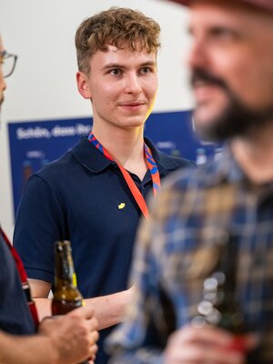 Ein junger Mann unterhält sich mit anderen Teilnehmenden beim BeerTalk.