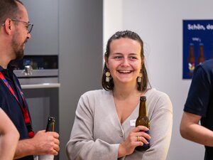Eine Frau lächelt mit einem Getränk in der Hand beim BeerTalk.