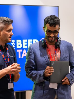 Zwei Männer stehen vor dem BeerTalk-Bildschirm und bereiten ihren Beitrag vor.