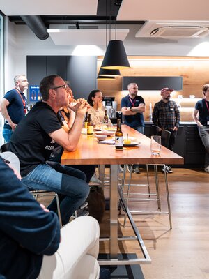 Teilnehmende sitzen und stehen im Veranstaltungsraum und verfolgen den BeerTalk.