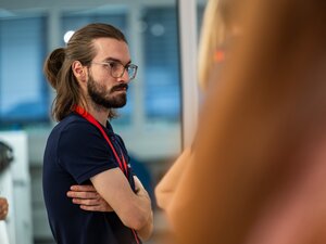 Ein Mann mit zusammengebundenen Haaren hört beim BeerTalk zu.